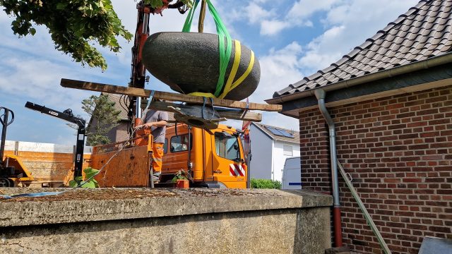 Der Brunnen wird zur Zwischenlagerung neben der ehem. Leichenhalle gestellt